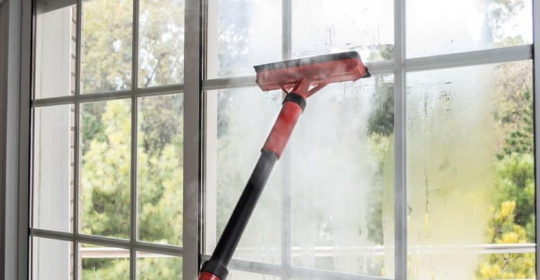 Steam cleaner cleaning a window with a squeegee